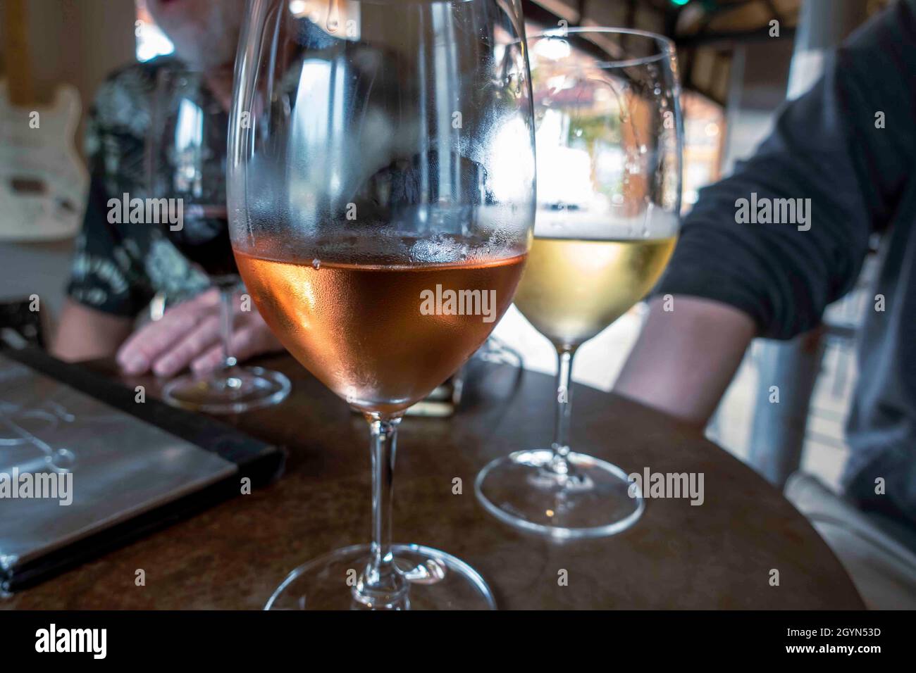 Nahaufnahme konzentriert euch auf ein Glas Rosé- und Weißwein an einem Tisch, an dem sich Freunde und Familie zu Weinproben versammelt haben Stockfoto