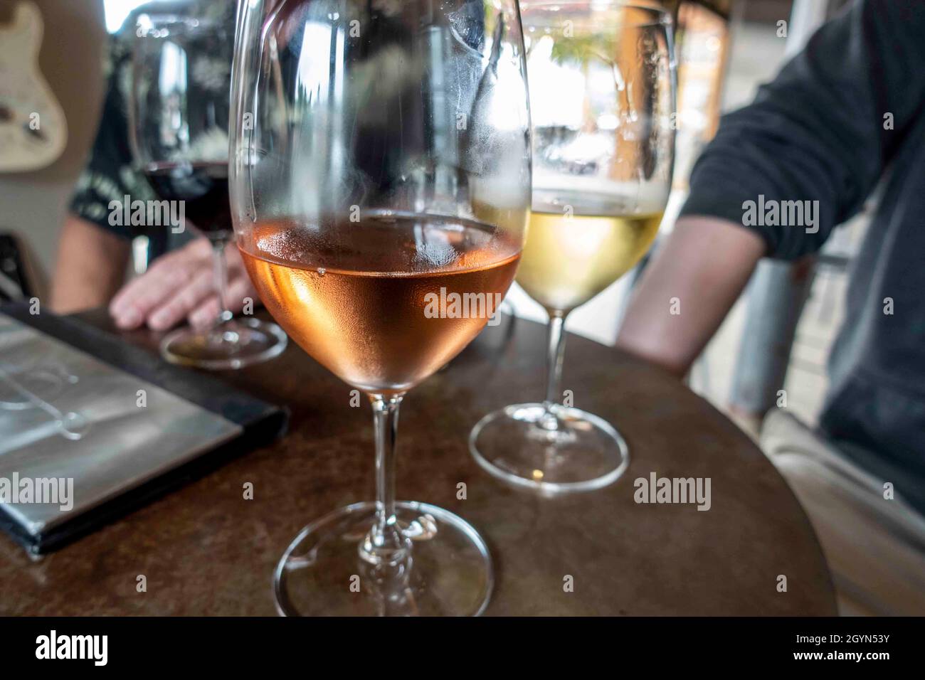 Nahaufnahme konzentriert euch auf ein Glas Rosé- und Weißwein an einem Tisch, an dem sich Freunde und Familie zu Weinproben versammelt haben Stockfoto