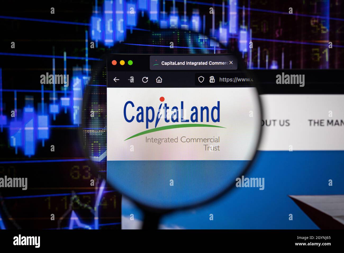 Firmenlogo von CapitaLand auf einer Website mit verschwommenen Börsenentwicklungen im Hintergrund, die auf einem Computerbildschirm durch eine Lupe gesehen werden Stockfoto