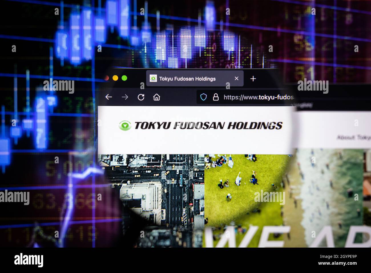 Tokyu Fudosan Holdings Firmenlogo auf einer Website mit verschwommenen Börsengraphen im Hintergrund, die auf einem Computerbildschirm zu sehen sind Stockfoto
