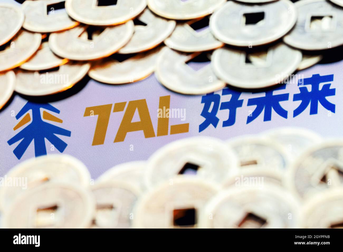TAL Education Group ist ein chinesisches Unternehmen, das Schulabklärungsunterricht für Schüler anbietet. TAL-Logo, umgeben von verschwommenen feng Shui-Münzen. Stockfoto