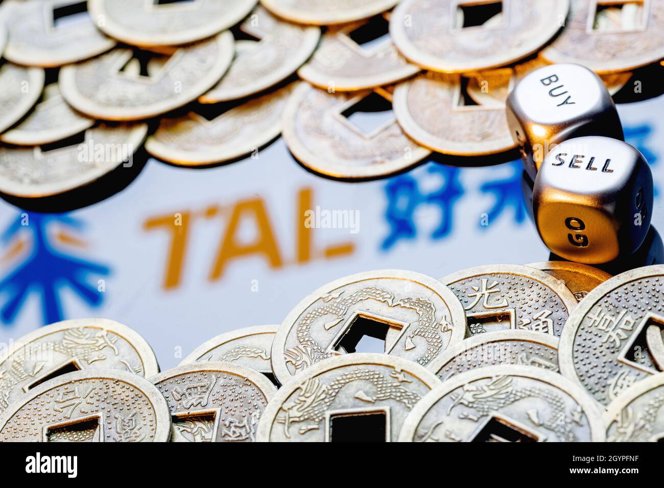 Würfel mit den Worten VERKAUFEN KAUFEN. TAL-Logo, umgeben von feng Shui-Münzen. Stockfoto