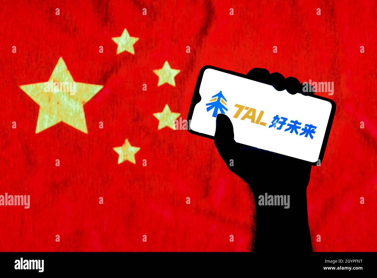 Ein Smartphone mit dem Tal-Logo in einer geballten Hand auf dem Hintergrund der chinesischen Flagge. Stockfoto