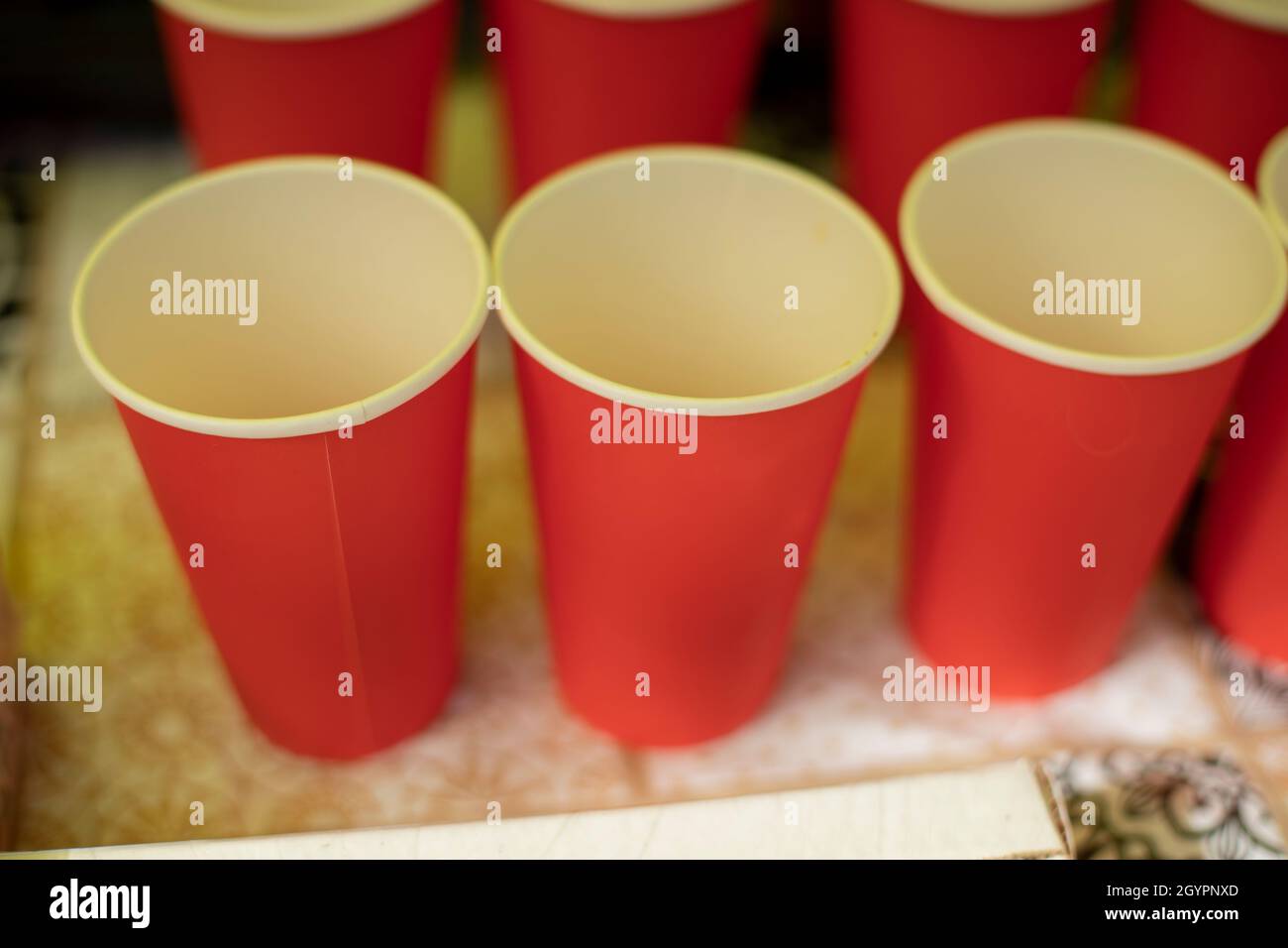 Leere Gläser. Rote Trinkbecher. Verteilung von Kaffee. Tisch mit Getränken. Papierutensilien. Stockfoto