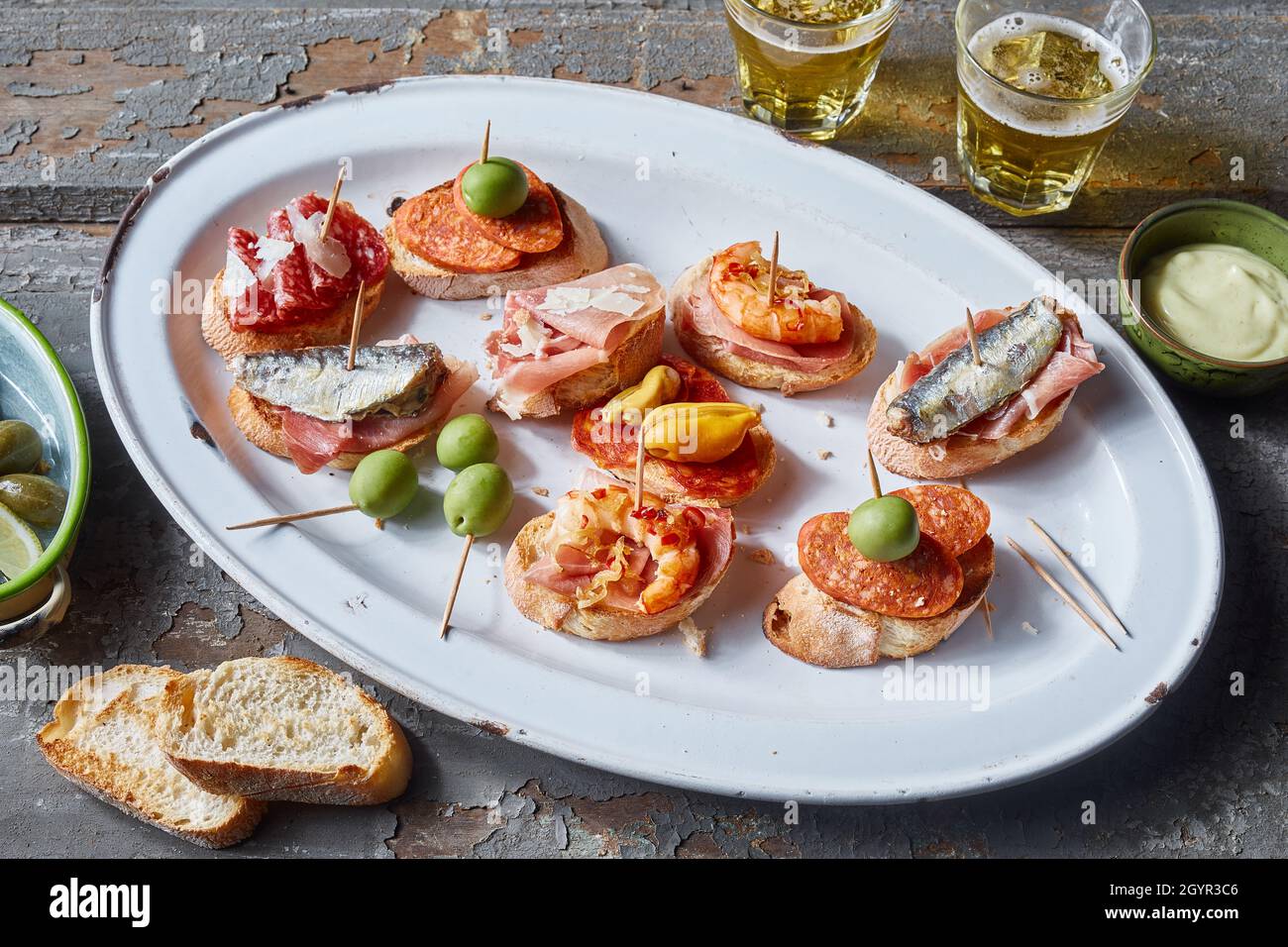 Von oben Teller mit appetitlichen Bruschettas mit Meeresfrüchten und Fleisch serviert auf Holztisch mit Bier Stockfoto