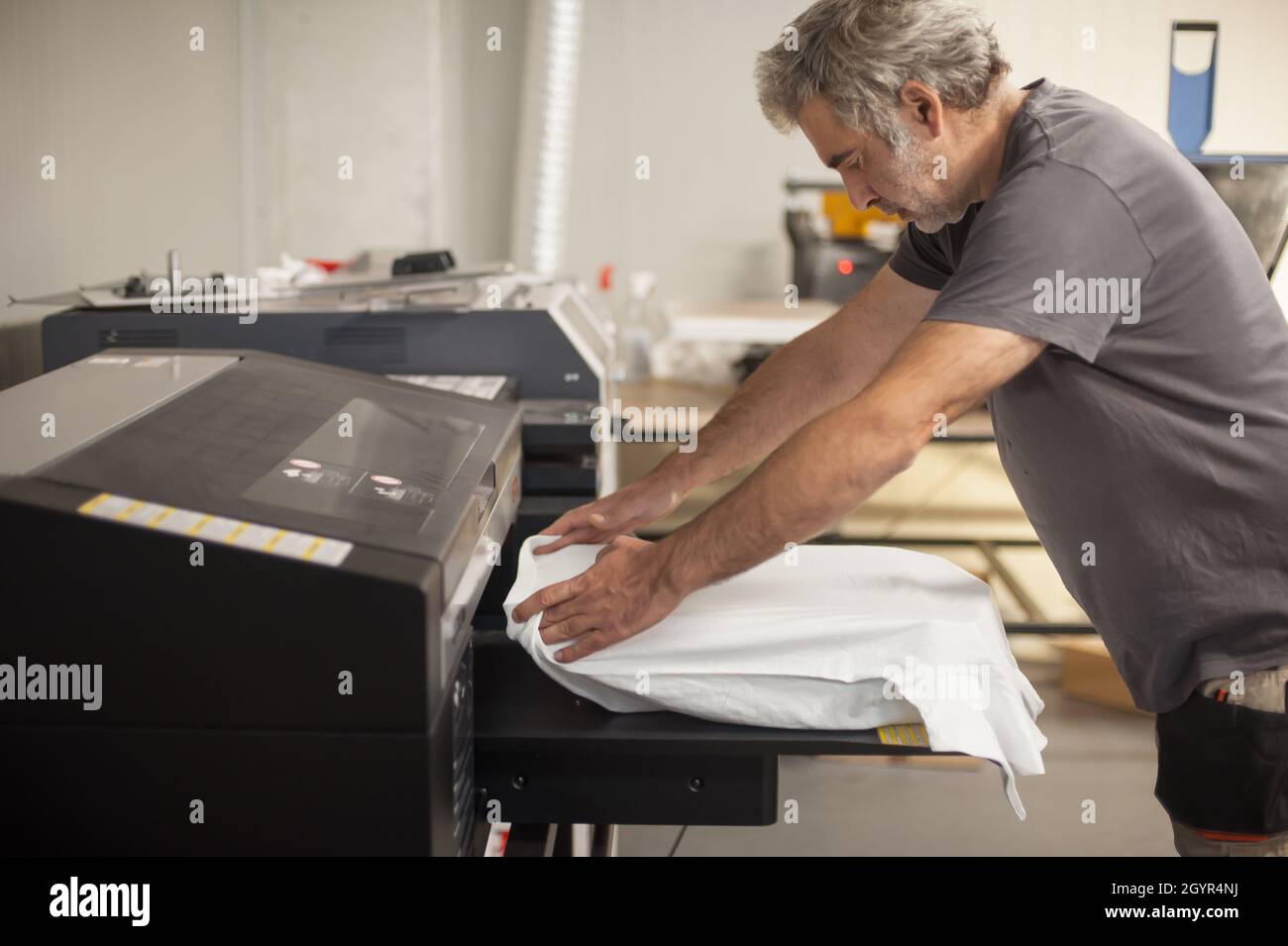 Professioneller Grafikdrucktechniker arbeitet an einem digitalen T-Shirt-Drucker  in der Druckerei Stockfotografie - Alamy