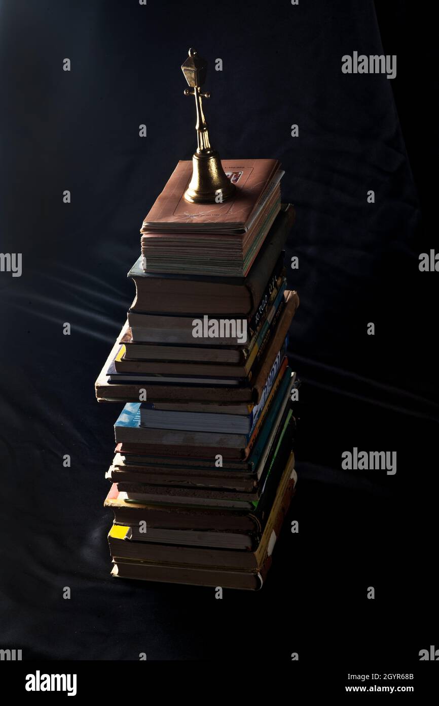 Dunkle und launische Fotografie eines Stapels alter getragener alter antiker Bücher vor einem dunkelschwarzen Hintergrund Stockfoto