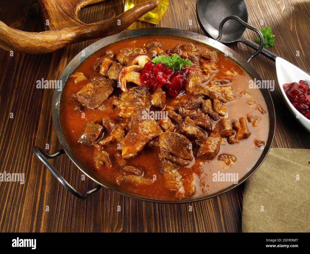 Wildfleisch Gulasch in einer Pfanne mit Cranberries auf Holzhintergrund Stockfoto