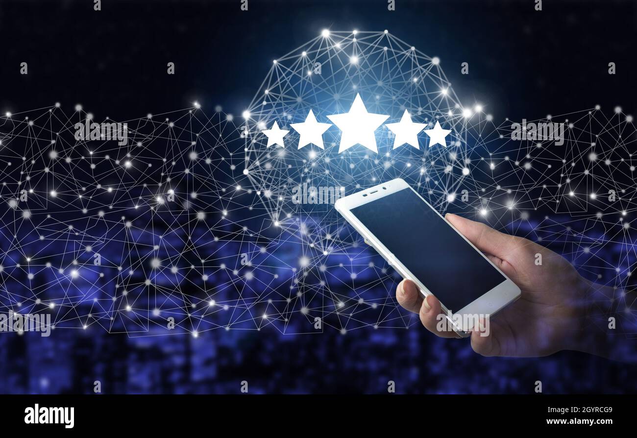 Bewertung, Bewertung, Zufriedenheit. Handgriff weißes Smartphone mit digitalem Hologramm fünf Sterne Zeichen auf Stadt dunkel verschwommen Hintergrund. Bewertung oder Rang erhöhen Stockfoto
