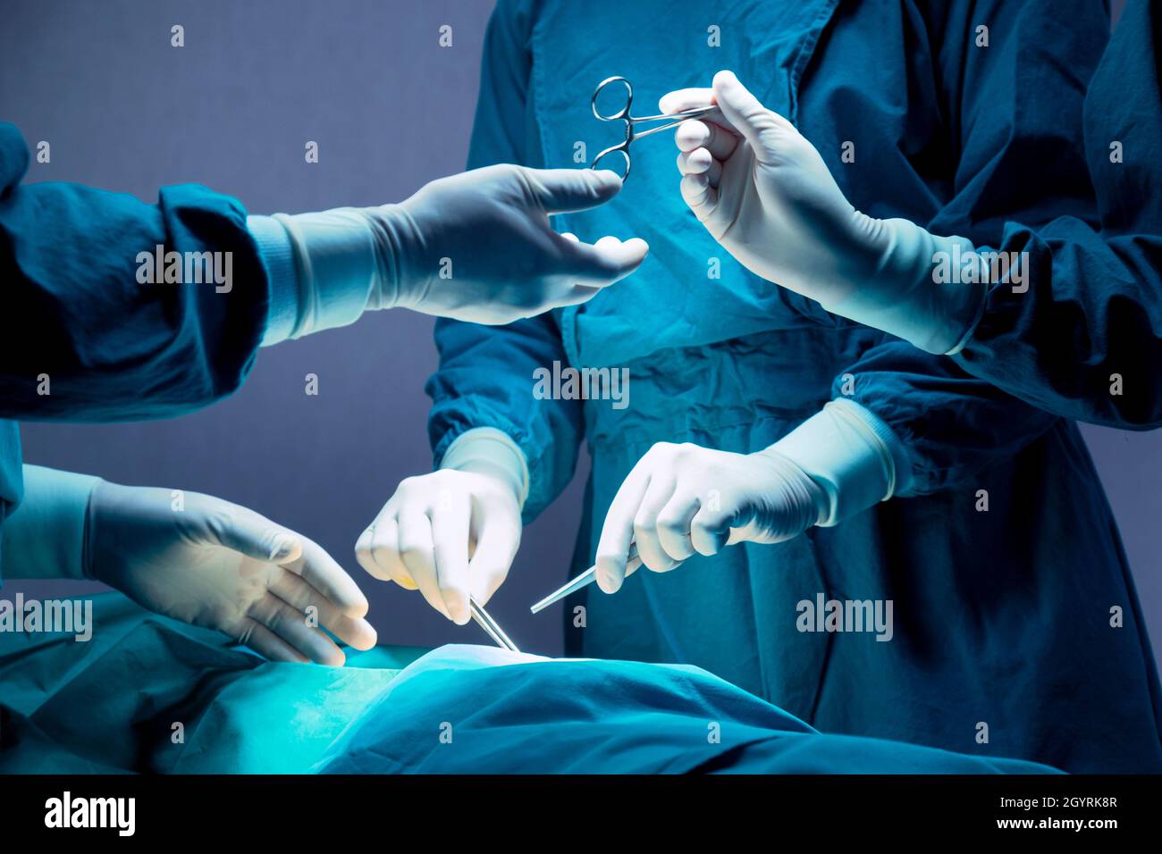 Das medizinische Team von Arzt und Krankenschwester führt eine Operation in der Notaufnahme im Krankenhaus durch. Der Assistent gibt Chirurgen eine Schere und Instrumente Stockfoto