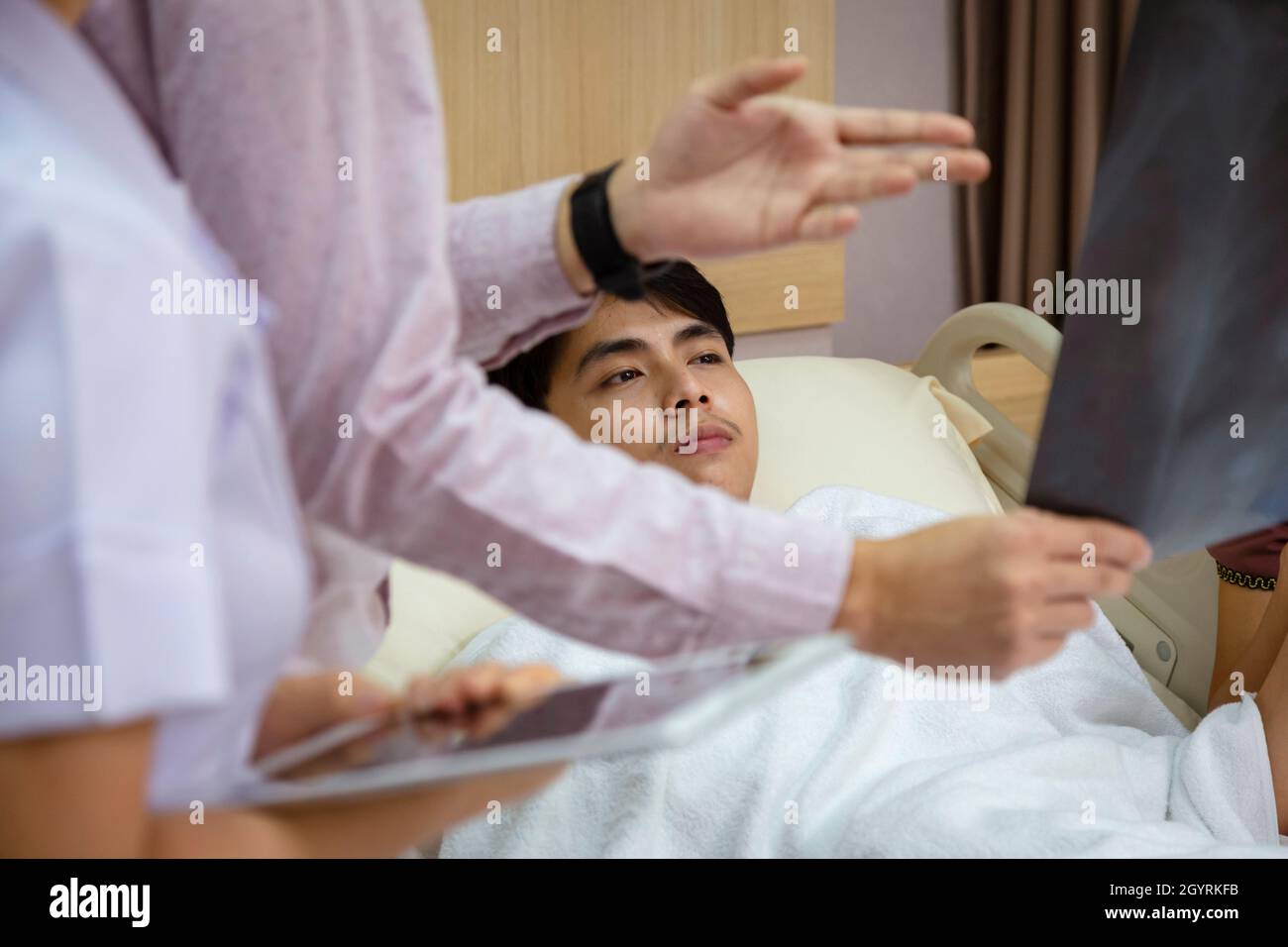 Arzt und Krankenschwester erklären dem asiatischen Patienten im Krankenhaus die Untersuchung des Röntgenfilmergebnisses der Brust und beraten ihn bei der Behandlung. Stockfoto