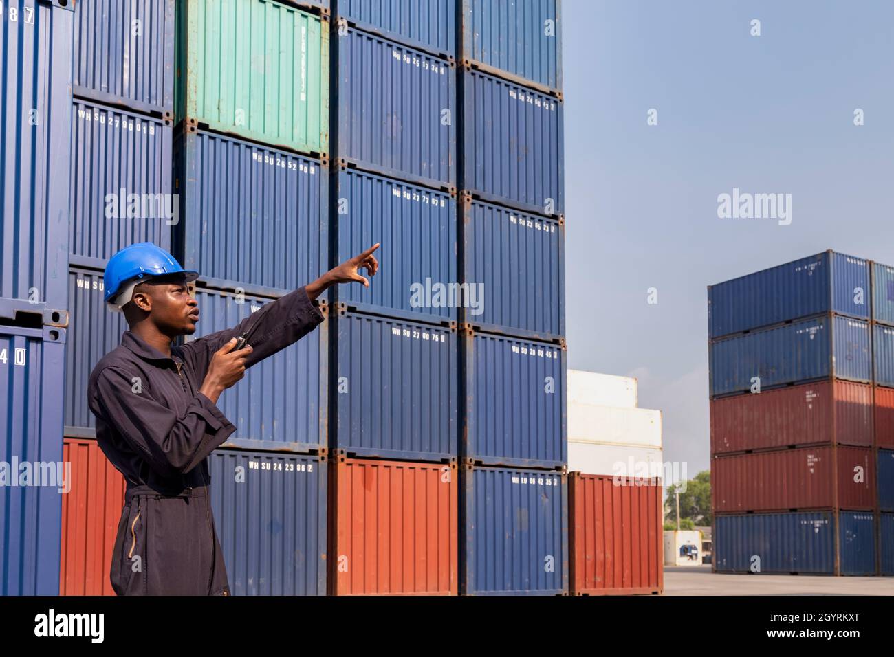 Schwarzer afrikanischer Amarikan Mann Arbeiter arbeiten Kontrolle Verladung Frachtcontainer an kommerziellen Schiffahrtsdock. Fracht Fracht Dock und Import Export logisti Stockfoto