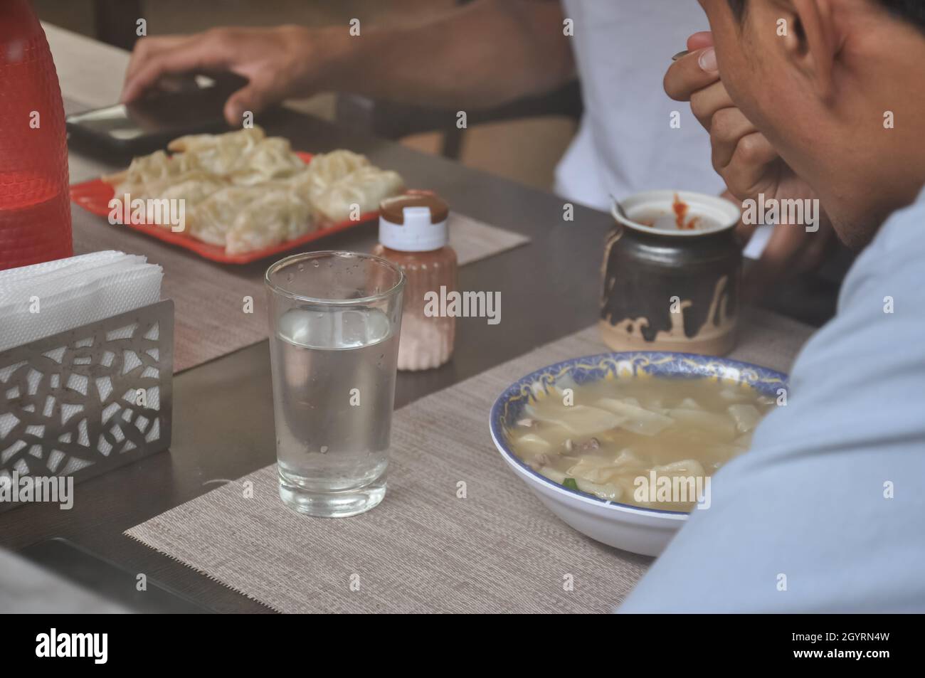 Selektiver Fokus auf Menschen, die tibetisches Essen in einem Indoor-Fast-Food-Café durch das Glasfenster sehen Stockfoto