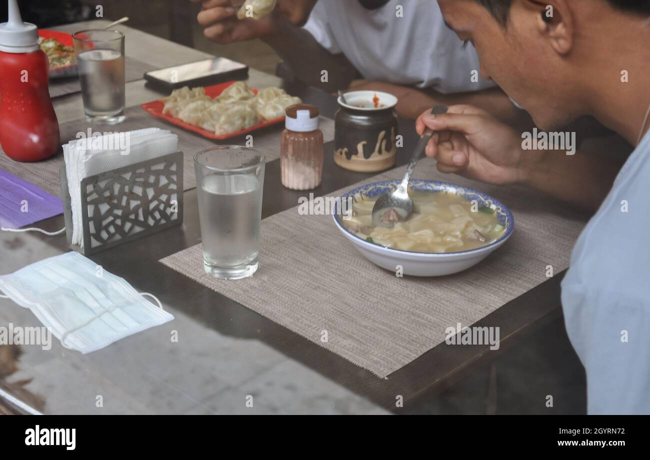 Menschen, die tibetisches Essen in einem Café im Innenbereich essen, das durch das Fenster gesehen wird Stockfoto