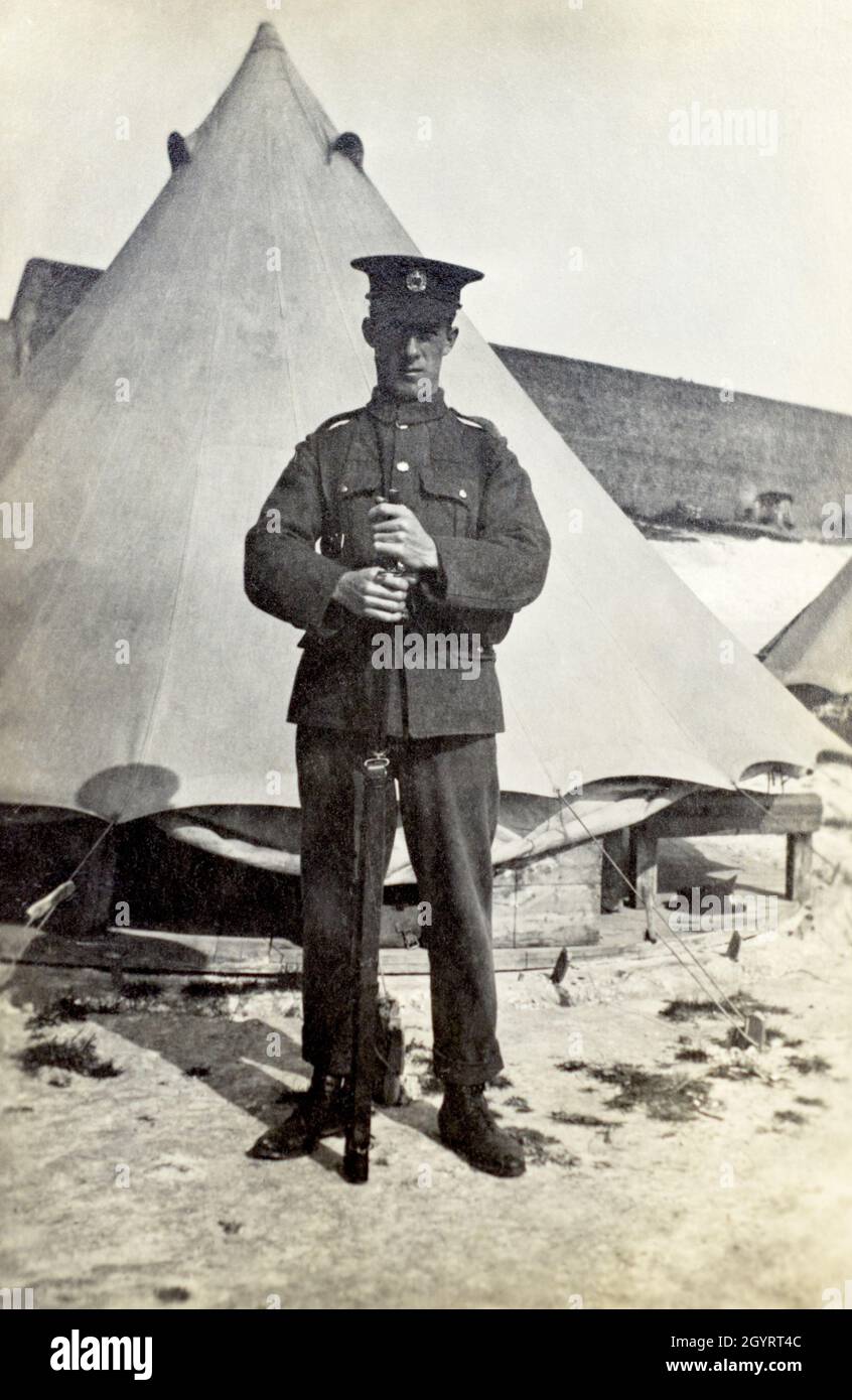 Ein Porträt eines Soldaten der britischen Armee, A. H. Stevens von den Royal Engineers, der mit seinem Gewehr vor einem Zelt in einem Lager in Dover, Kent, England, Großbritannien, stand. Vom 1915. Im Zelt ist ein Holzboden zu sehen. Stockfoto