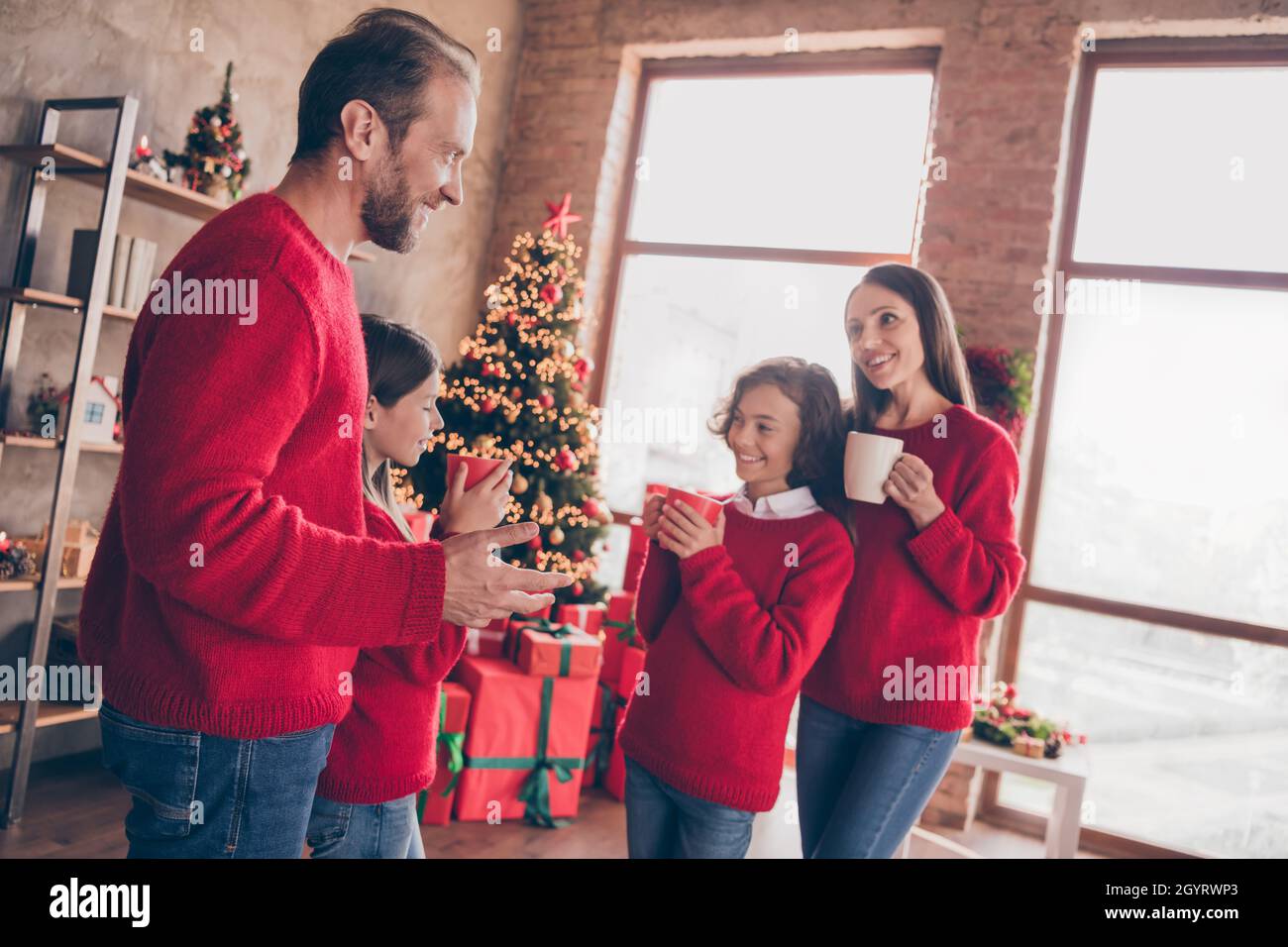 Foto von positiven verträumten Familie halten Tasse trinken Tee Kakao immergrünen Baum Girlande in dekorierten Weihnachten Zuhause drinnen Stockfoto