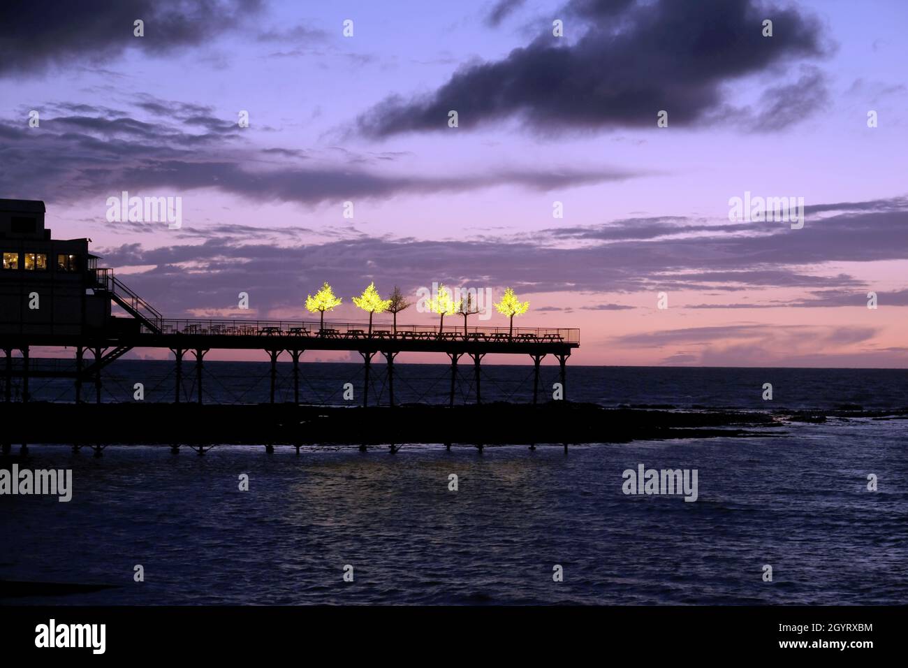 Beleuchtete Imitationsbäume am Royal Pier, Aberystwyth, West Wales, Großbritannien. Bei Sonnenuntergang leuchten die Lichter hell Stockfoto
