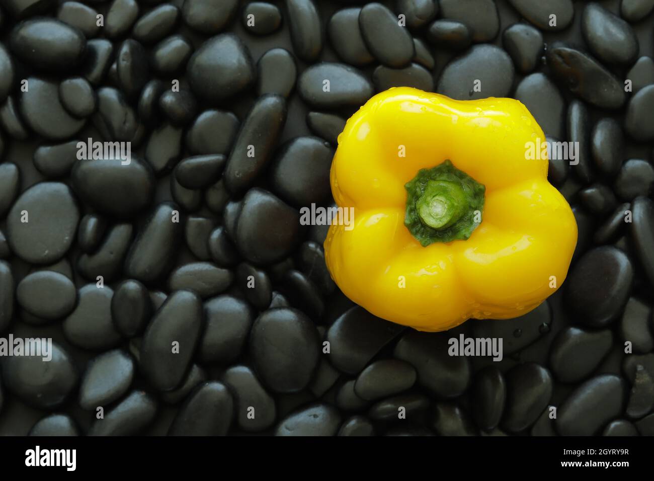 Draufsicht eine gelbe Paprika auf blackstone mit glatter, glänzender Haut und rundem Rand. Schwarzer Stein Hintergrund machen gelben Paprika aussehen standou Stockfoto