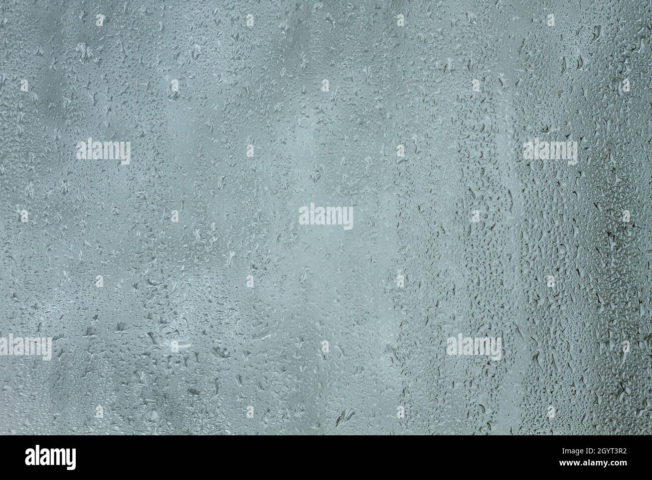 Kondenswassertropfen auf einem Glasfenster schließen sich an Stockfoto