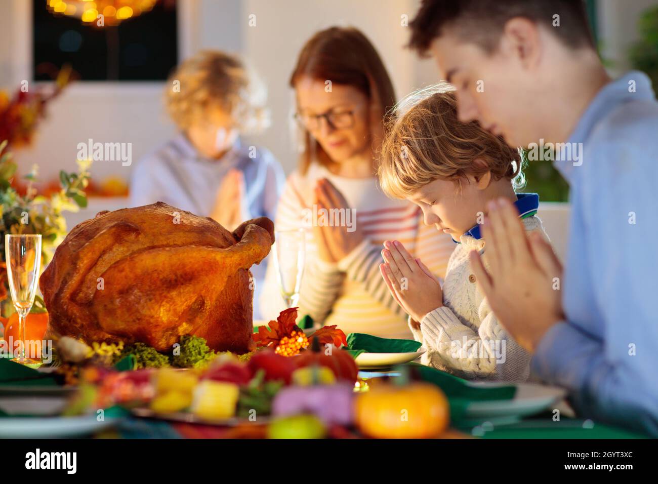 Familie am Thanksgiving-Abendessen. Eltern, Großeltern und Kinder genießen geröstete pute- und Gemüsemahlzeiten. Kinder und Großmutter sagen ein dankbares Gebet. Stockfoto