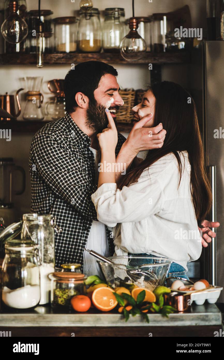 Junge glückliches Paar mit Mehl auf Gesichtern Backen Zitruskuchen Stockfoto