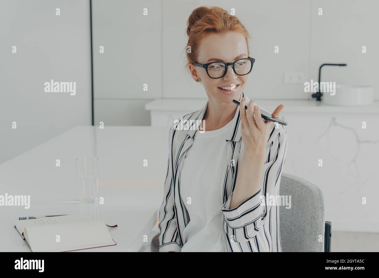 Lächelnde Rotschopf Frau verwendet virtuelle Sprachassistent nimmt Audio-Nachricht Stockfoto