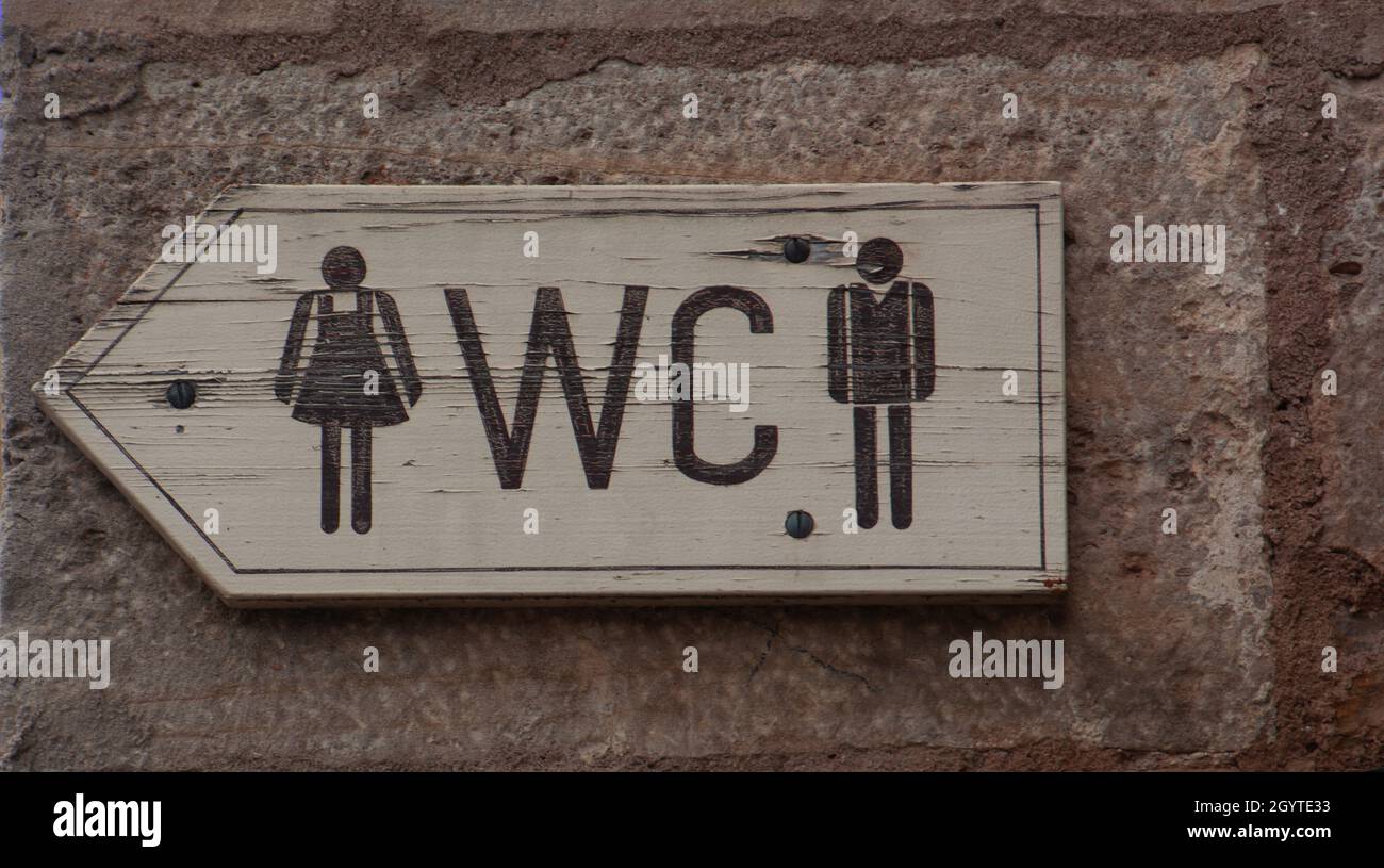 WC-Schild oder Logo der öffentlichen Toiletten aus Holz an der alten Stadtmauer Stockfoto