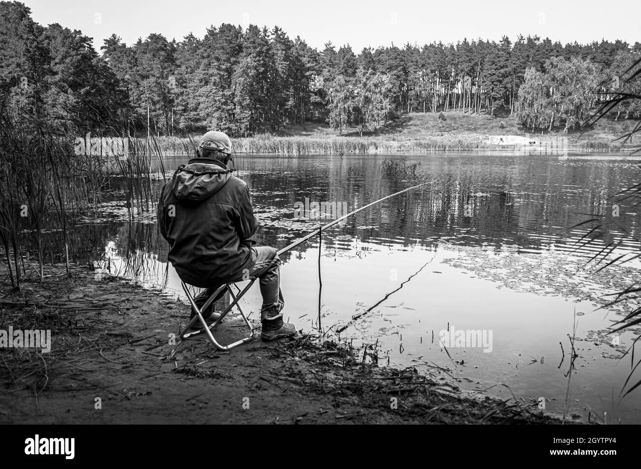 Einsamer Fischer, der vor dem Rabiga Kul See in der ländlichen Gegend von Bolgar, Tatarstan, sitzt. Schwarz und Weiß. Stockfoto