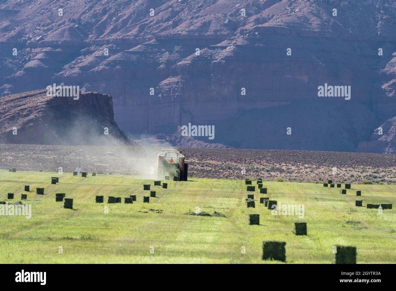 Heuballenpressen mit einem John Deere Traktor 7930 und einer GPT Twin Pak Ballenpresse auf einer Ranch im Süden von Utah. Stockfoto