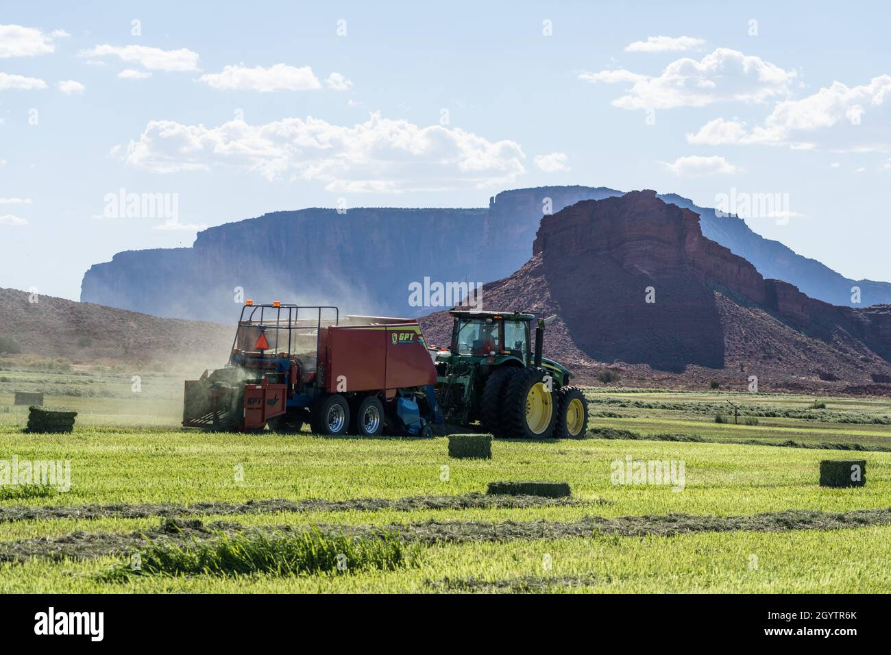 Heuballenpressen mit einem John Deere Traktor 7930 und einer GPT Twin Pak Ballenpresse auf einer Ranch im Süden von Utah. Stockfoto