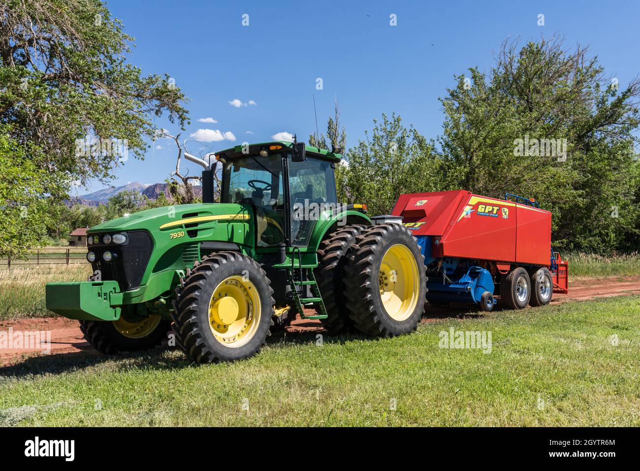 Heuballenpressen mit einem John Deere Traktor 7930 und einer GPT Twin Pak Ballenpresse auf einer Ranch im Süden von Utah. Stockfoto