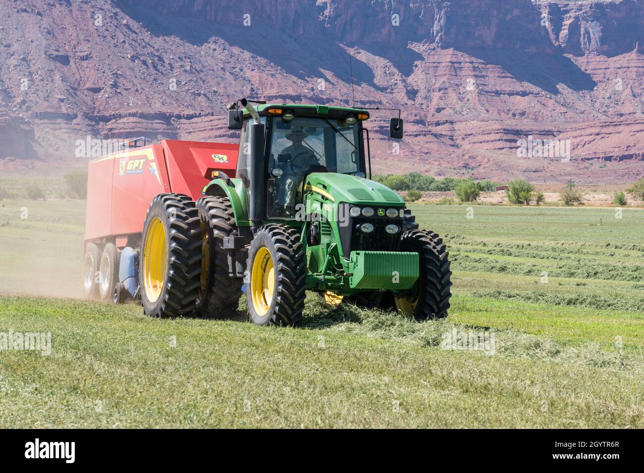 Heuballenpressen mit einem John Deere Traktor 7930 und einer GPT Twin Pak Ballenpresse auf einer Ranch im Süden von Utah. Stockfoto
