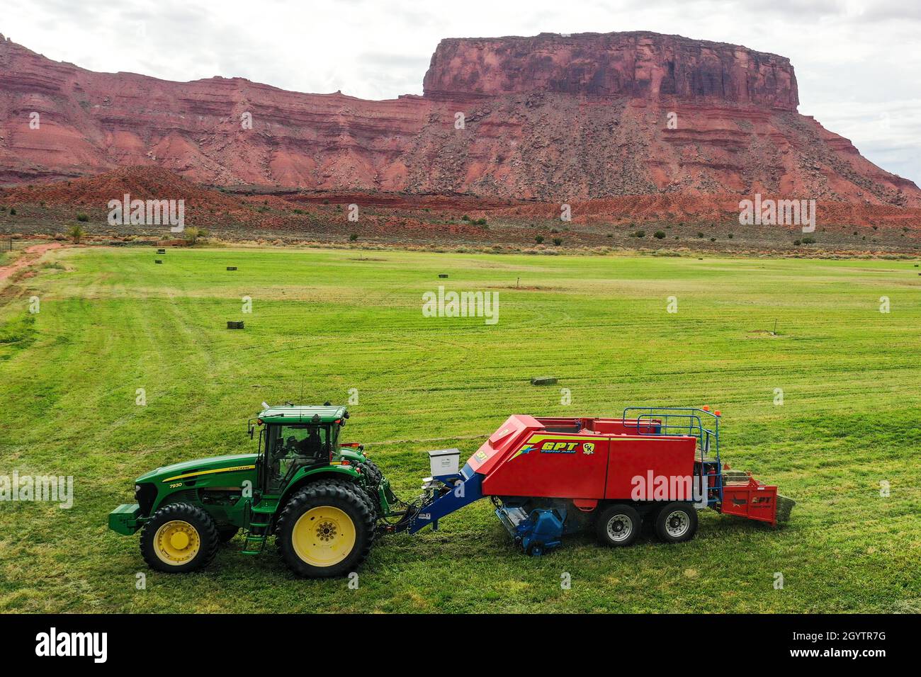 Eine Drohnenansicht eines Ranchers, der einen Traktor fährt und Heu auf einer Ranch im Canyon-Land von Utah ballt. Stockfoto