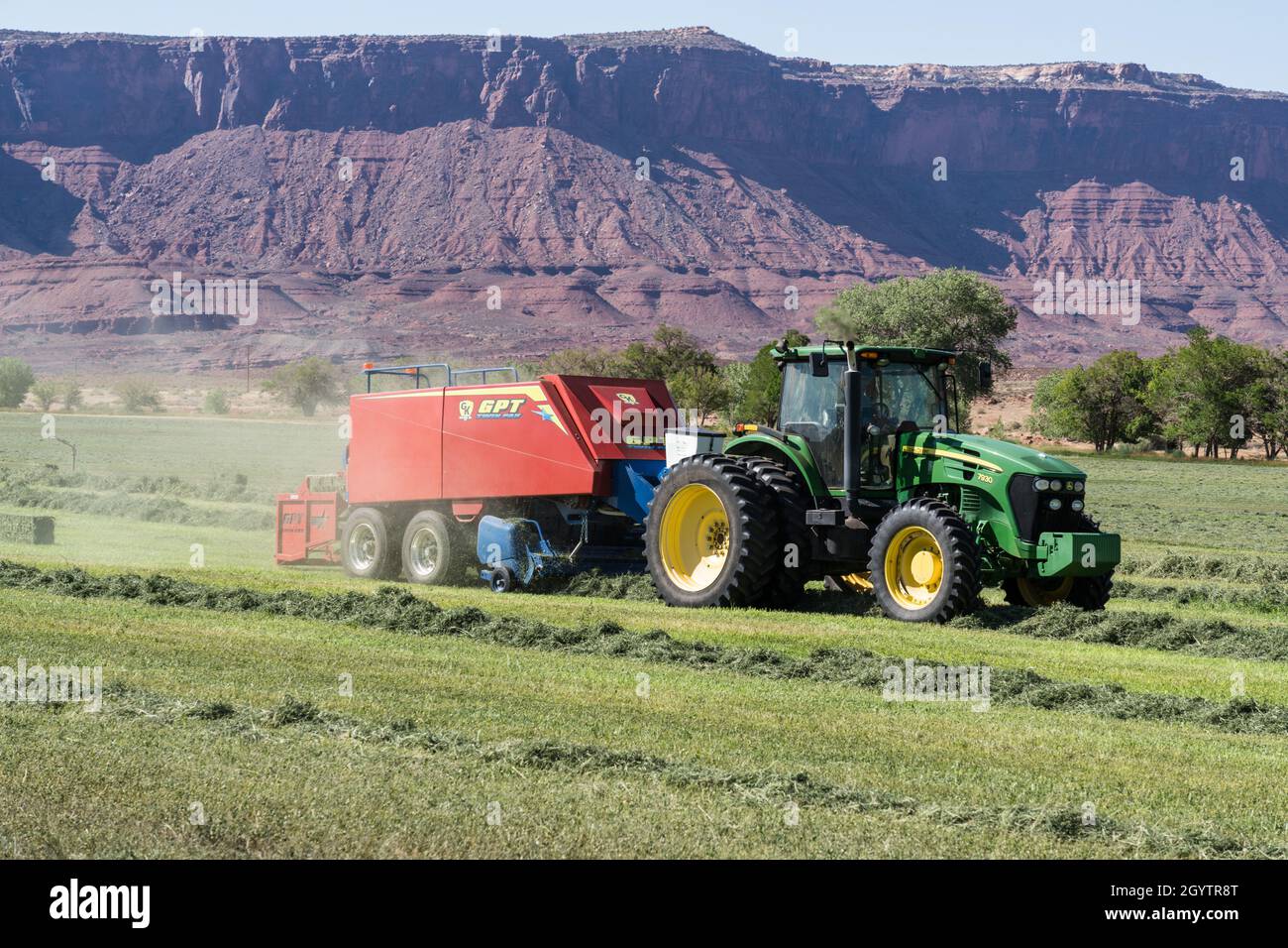 Heuballenpressen mit einem John Deere Traktor 7930 und einer GPT Twin Pak Ballenpresse auf einer Ranch im Süden von Utah. Stockfoto