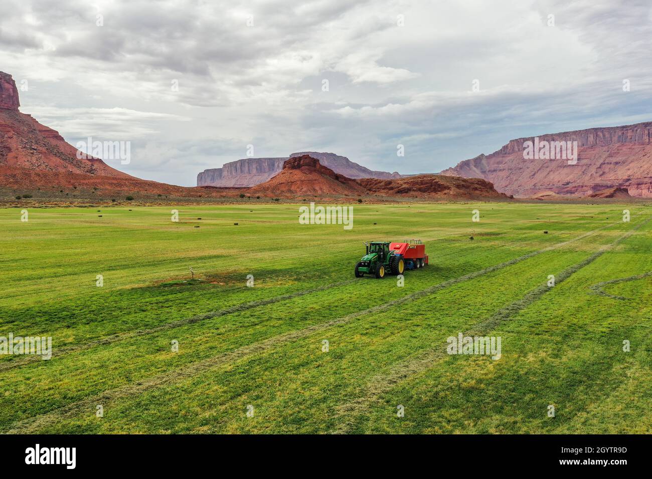 Eine Drohnenansicht eines Ranchers, der einen Traktor fährt und Heu auf einer Ranch im Canyon-Land von Utah ballt. Stockfoto