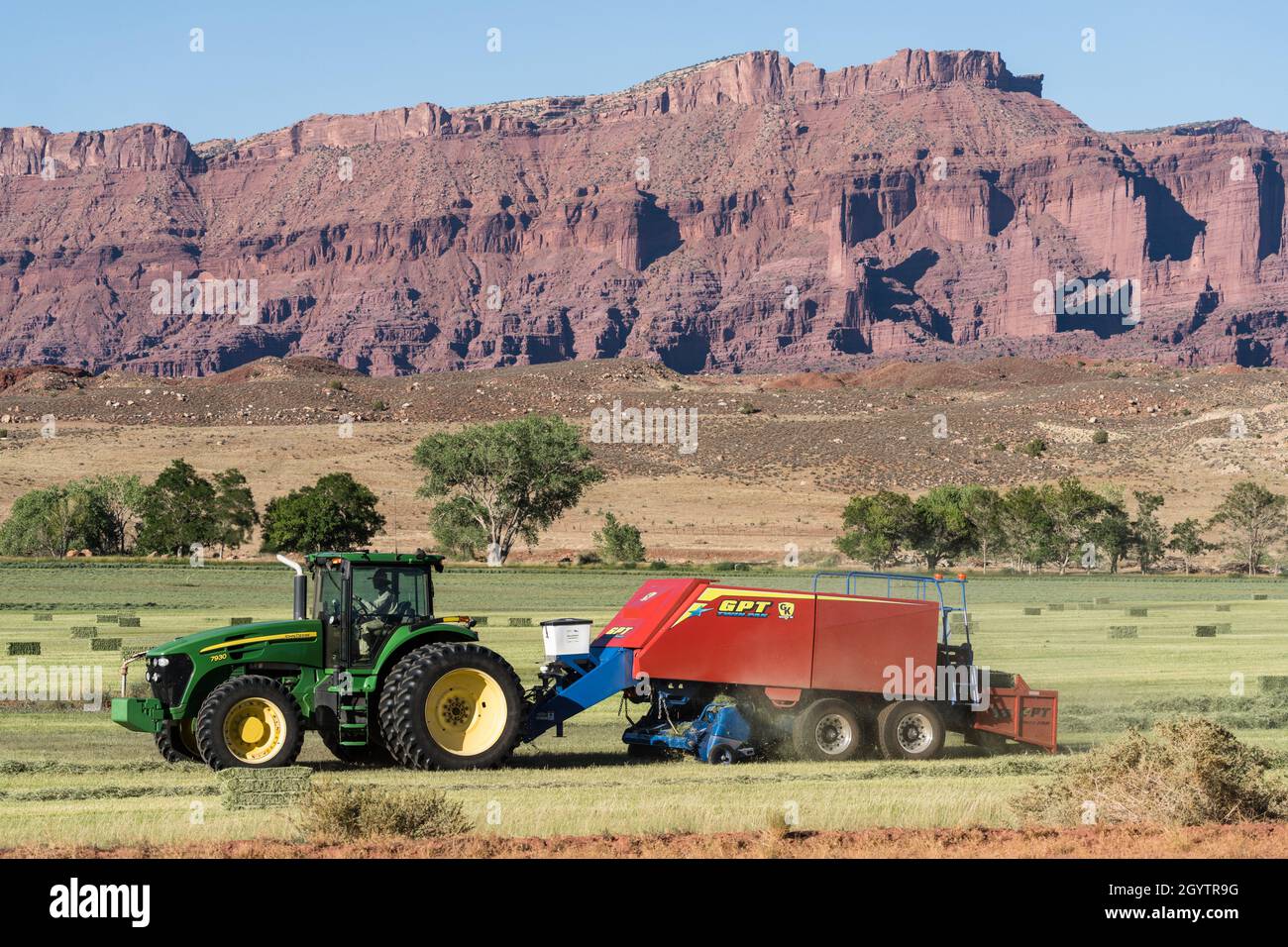 Heuballenpressen mit einem John Deere Traktor 7930 und einer GPT Twin Pak Ballenpresse auf einer Ranch im Süden von Utah. Stockfoto