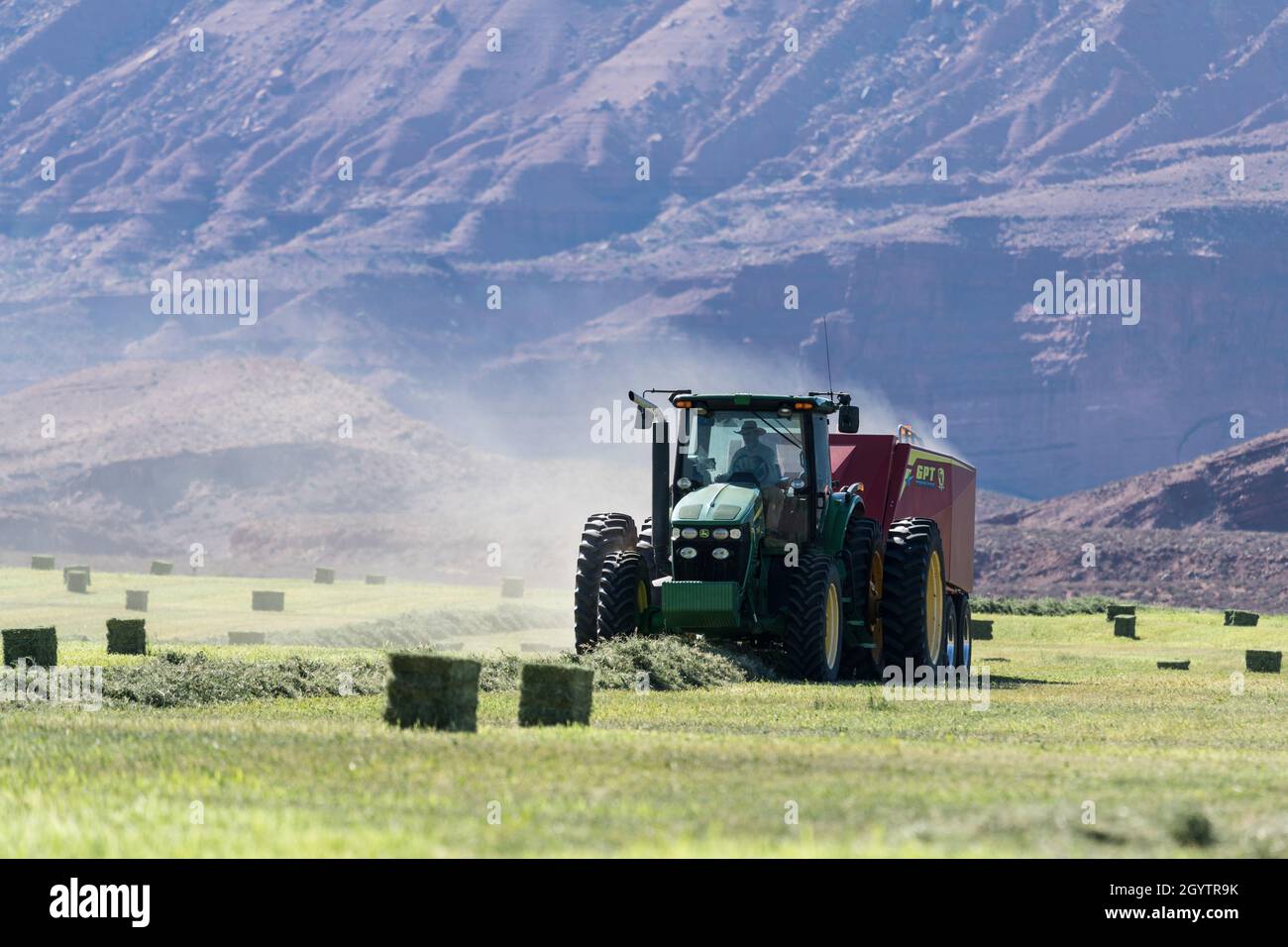 Heuballenpressen mit einem John Deere Traktor 7930 und einer GPT Twin Pak Ballenpresse auf einer Ranch im Süden von Utah. Stockfoto