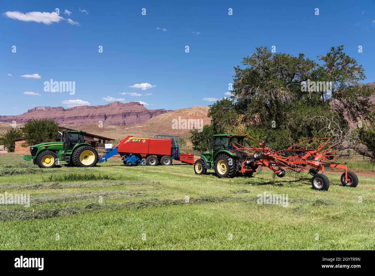 Eine GPT Twin Pak-Heupresse und ein Kuhn Twin Rotor Rake, die an John Deere-Traktoren auf einer Ranch in Utah befestigt sind. Stockfoto