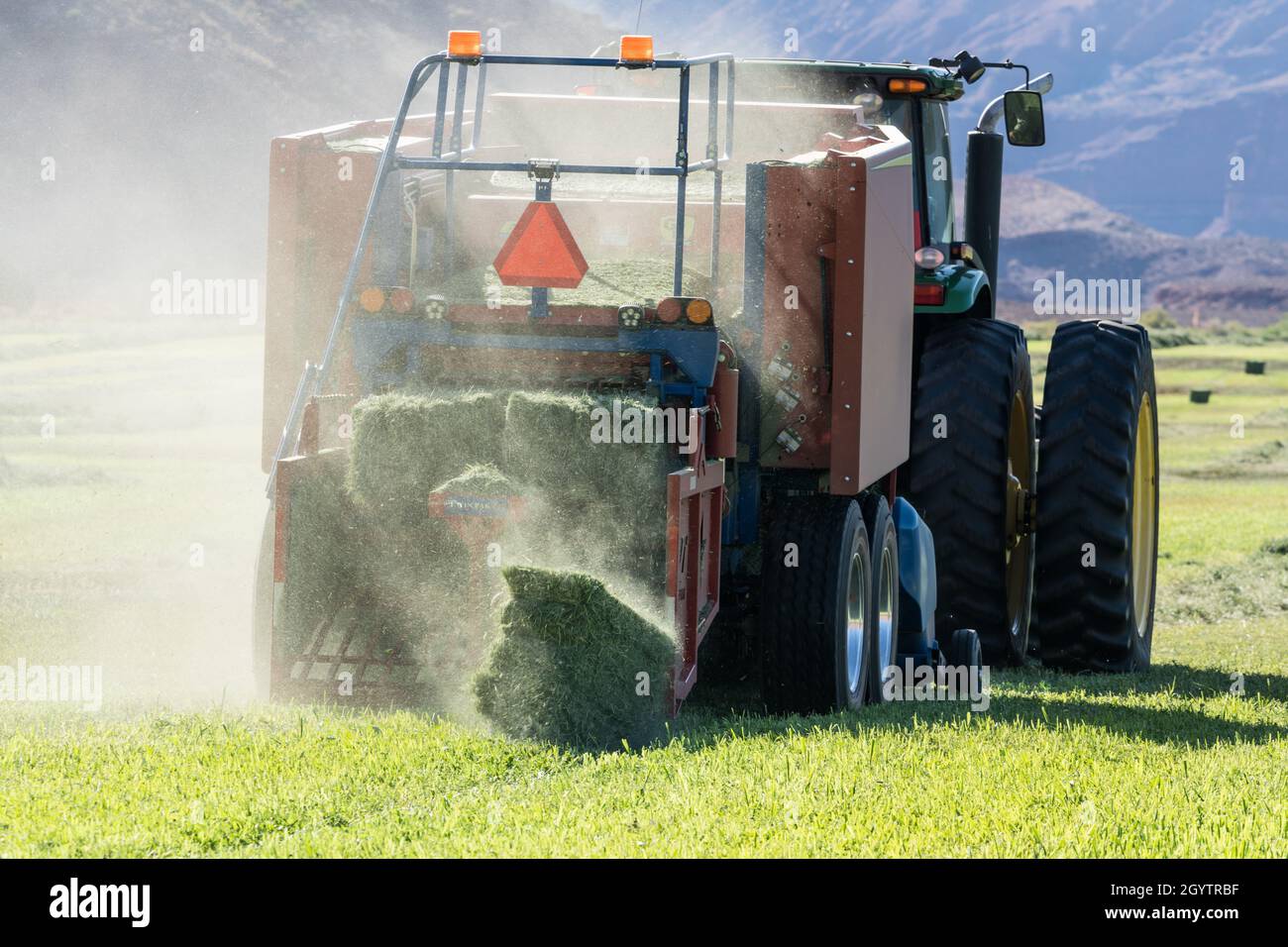 Heuballenpressen mit einem John Deere Traktor 7930 und einer GPT Twin Pak Ballenpresse auf einer Ranch im Süden von Utah. Stockfoto