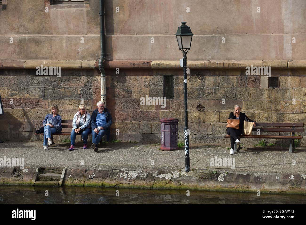 Menschen sitzen entspannt auf öffentlichen Sitzbänken am Fluss in Straßburg, Frankreich, 2021 Stockfoto