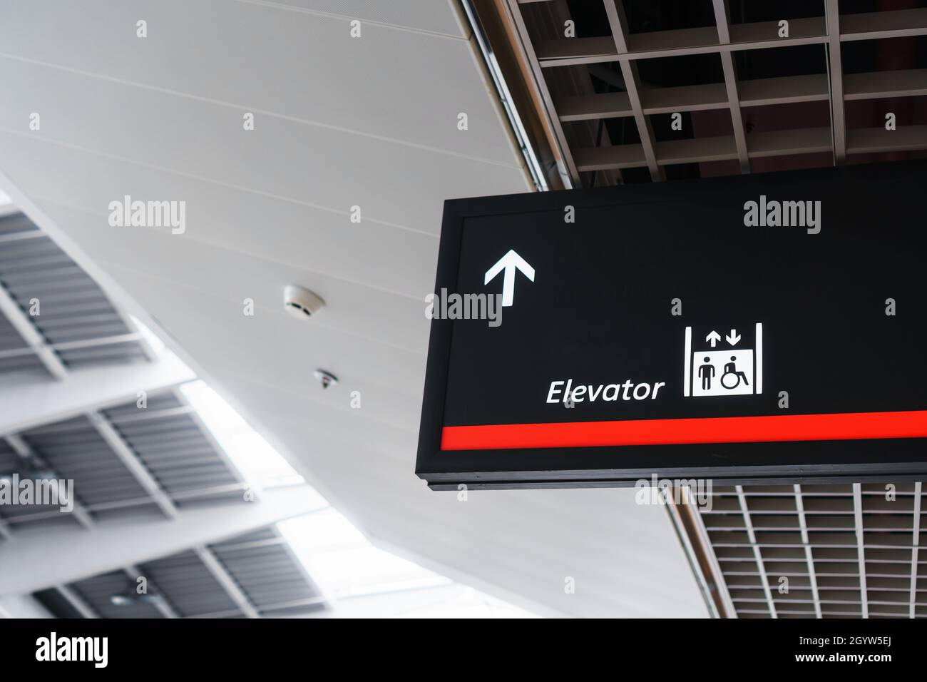 Ein Schild mit einem Pfeil, der auf den Aufzug im Wartepol des Flughafens zeigt. Speicherplatz kopieren Stockfoto