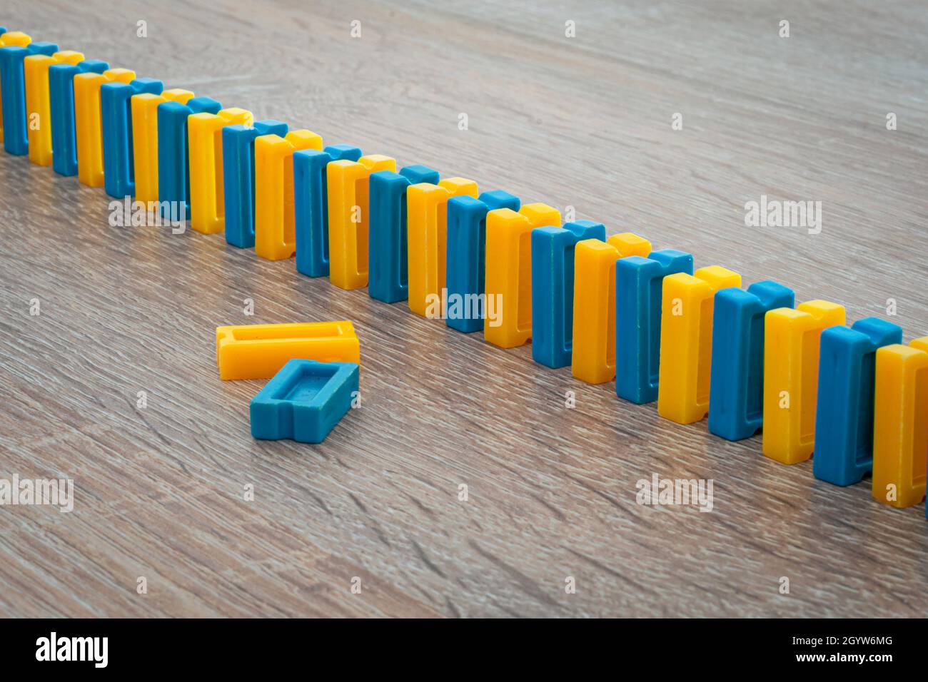 Reihe von kleinen gelben und blauen Dominosteinen. Konzept des fallenden Dominoeffekts. Stockfoto