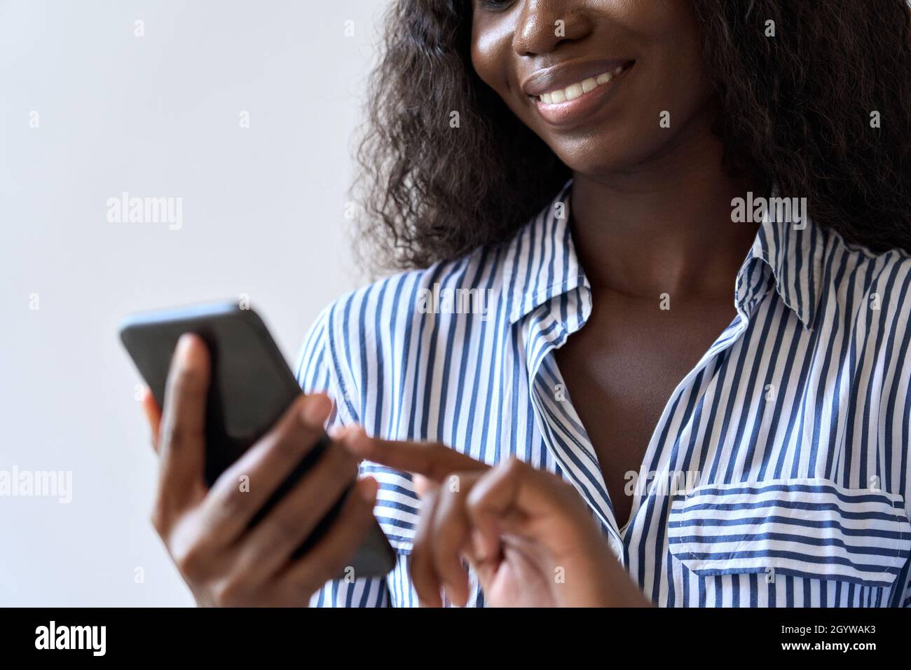 Junge lächelnde schwarze afrikanische Frau hält Smartphone in der Hand mit der mobilen App. Stockfoto