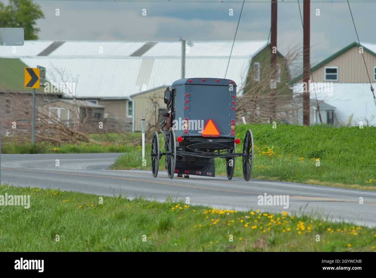 Ein Amish Horse und Buggy Reisen entlang einer Landstraße durch Ackerland an einem Frühlingstag Stockfoto