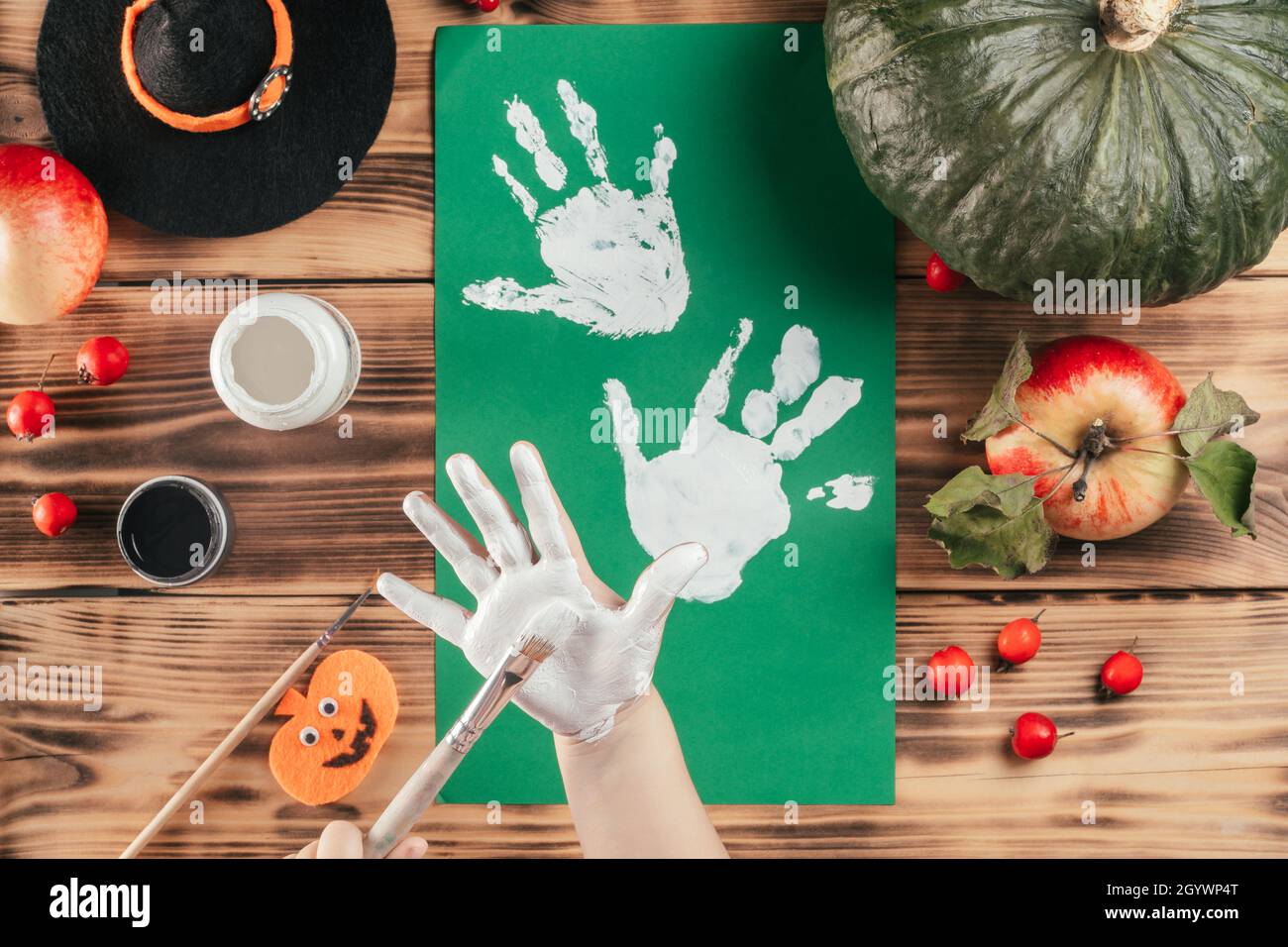 Schritt-für-Schritt Halloween Tutorial Geister Kinder Handprint. Schritt 5: Das Kind trägt mit dem Pinsel weiße Farbe auf die Handfläche auf. Draufsicht Stockfoto