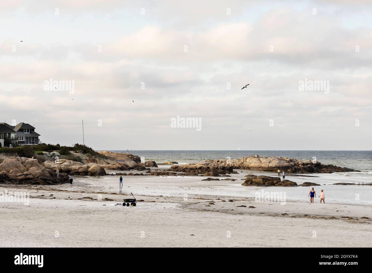 Ein paar Leute gehen an einem bewölkten Herbsttag bei Ebbe am Strand von Wingaersheek in Gloucester, Massachusetts, USA. Stockfoto