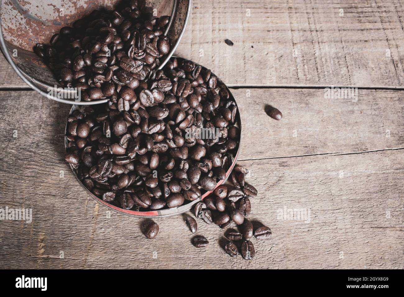 Vintage-Kaffeekapsel mit Kaffeebohnen, die auf Deckel und Holzhintergrund auslaufen Stockfoto