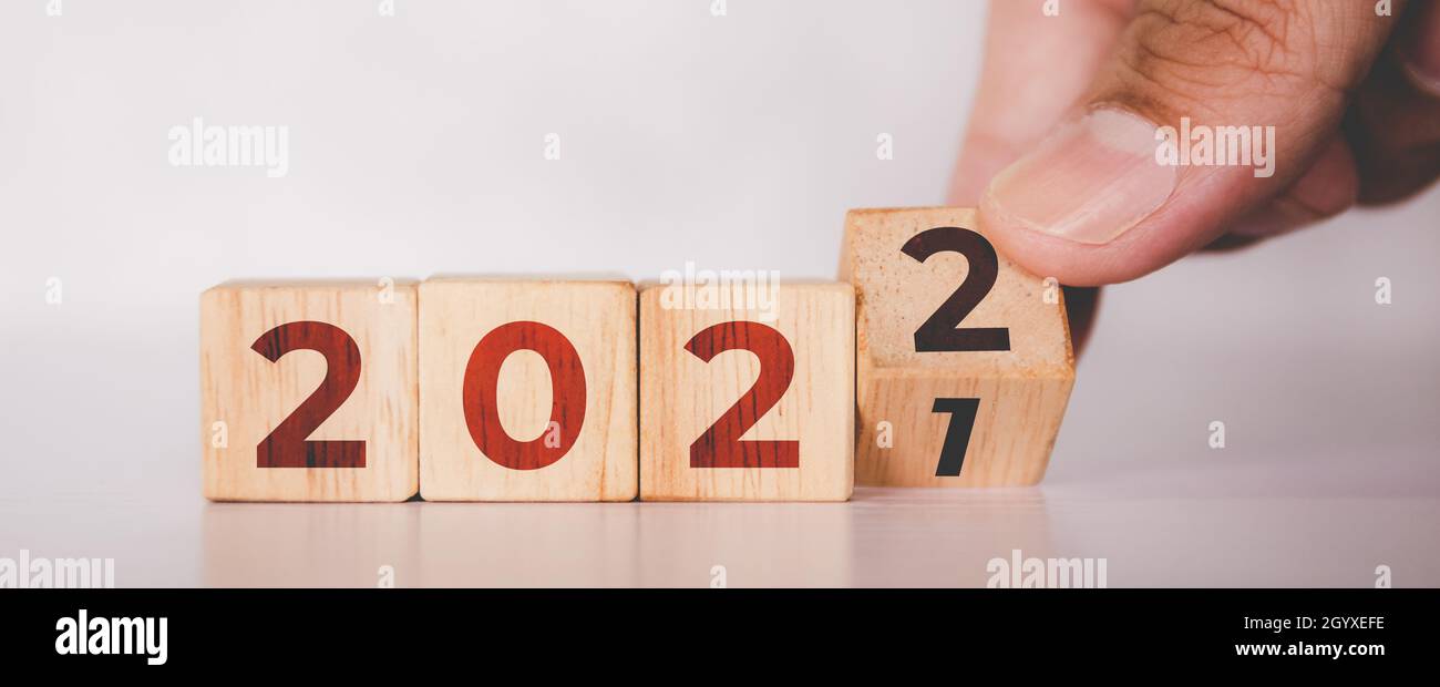 Hände kippender Würfel Holzblock mit Textjahr 2022, Anfang und Trend, Kalender und Zeit, Zielstrebigkeit und Planung für die Verwirklichung, Motiv Stockfoto