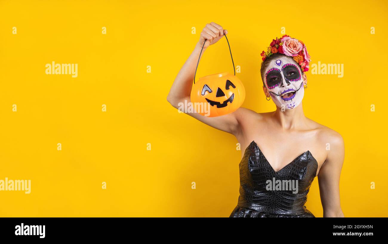 Mexikanische Catrina, Porträt einer jungen lateinerin, die einen Kunststoff-Kürbis aus Kalaverita für die Halloween-Party in Mexiko hält Stockfoto