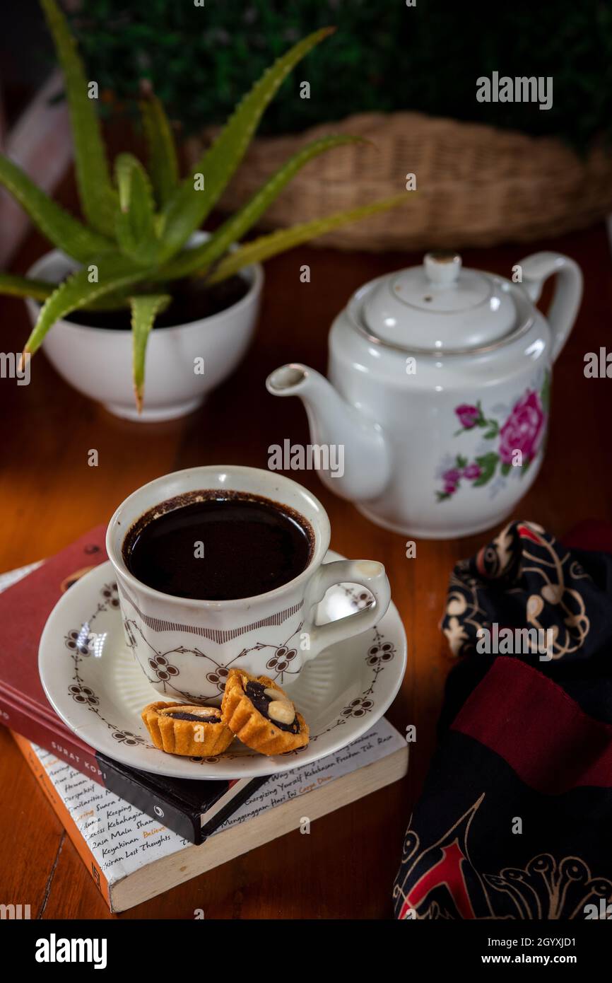 Eine Tasse schwarzen Kaffee mit einem Hintergrund aus Aloe Vera Blumen als Ergänzung zum Foto Stockfoto